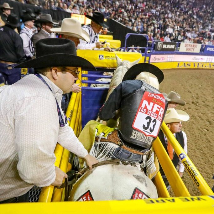 Westin Barnes prepares to flank his bareback horse at the 2022 WNFR